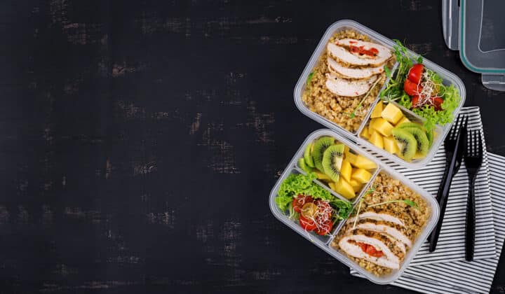 Single meal prep lunch box with chicken, bulgur, tomato, and fruit, top view