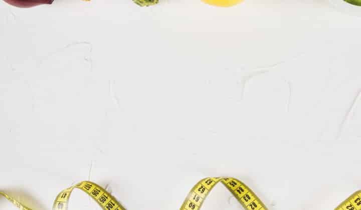 Overhead flat lay of lean protein and vegetables with a measuring tape, representing portion control for low-calorie high-protein meal prep