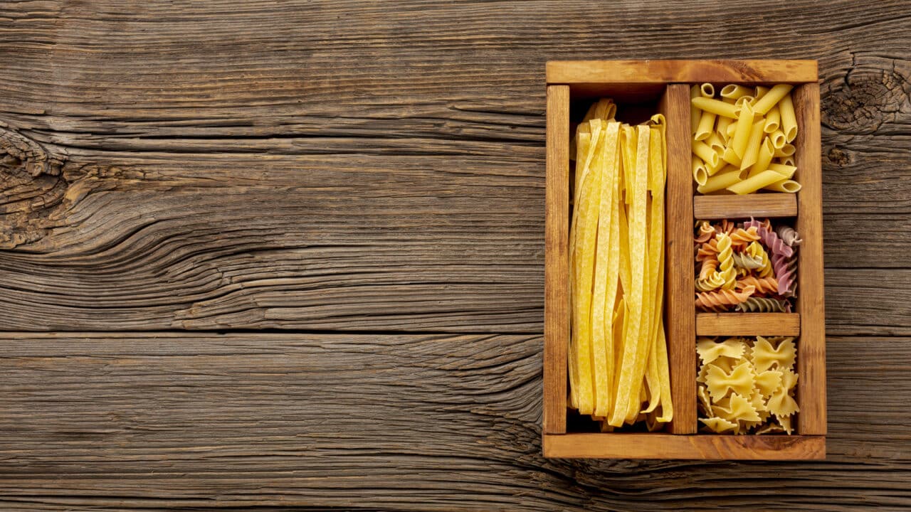 Uncooked pasta stored in a wooden box, used to illustrate pasta and mashed potatoes fridge storage times