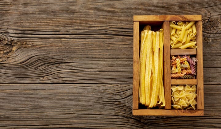 Uncooked pasta stored in a wooden box, used to illustrate pasta and mashed potatoes fridge storage times