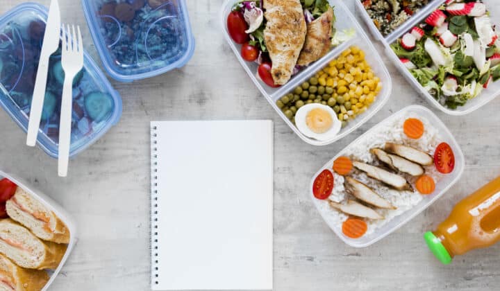 Meal prep containers arranged next to a planning notebook, top view flat lay