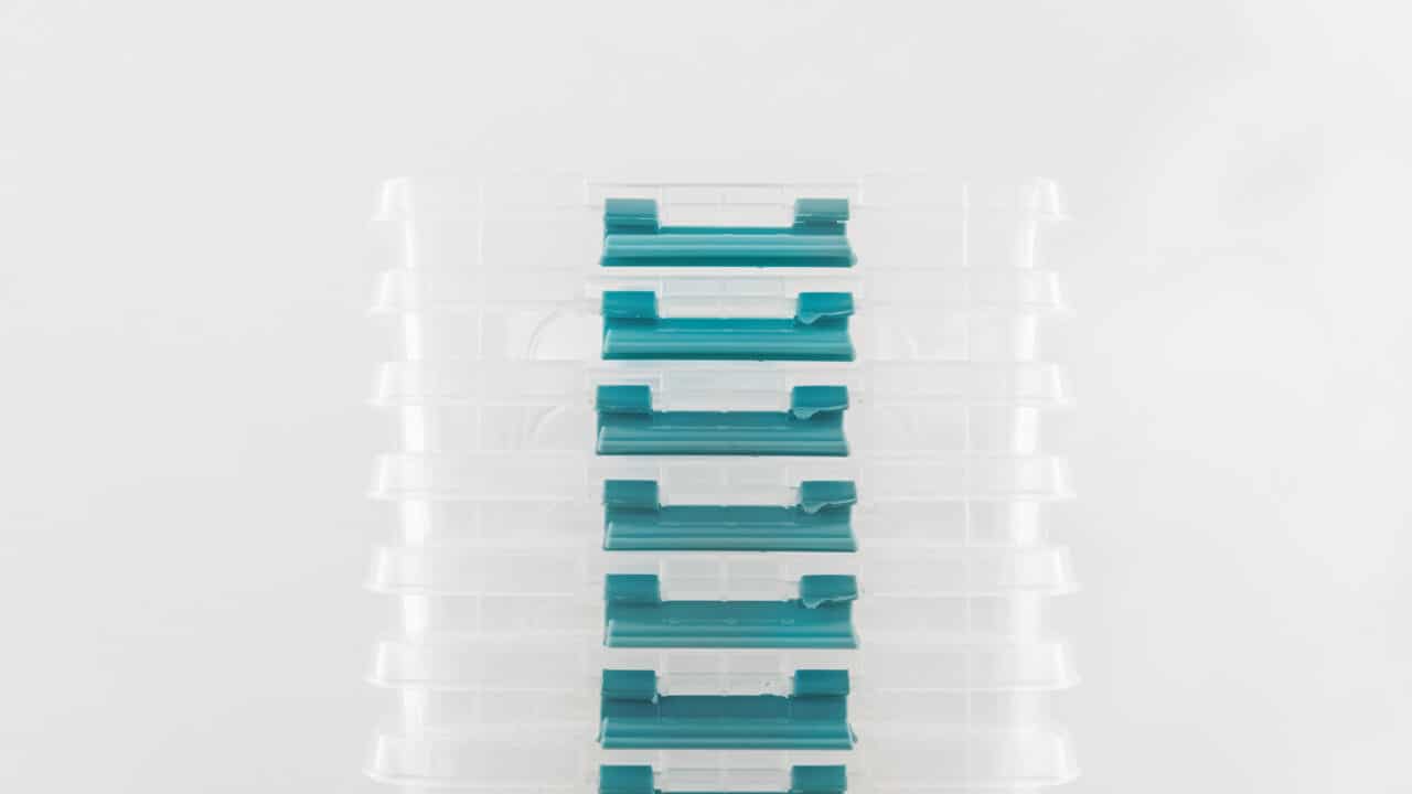 Stack of plastic meal prep containers with lids on a neutral surface