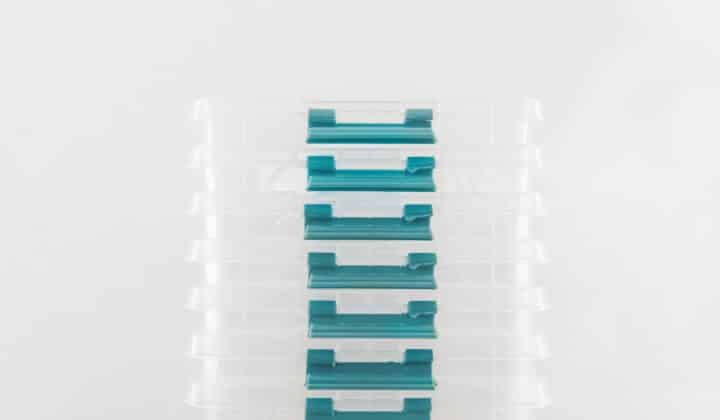 Stack of plastic meal prep containers with lids on a neutral surface