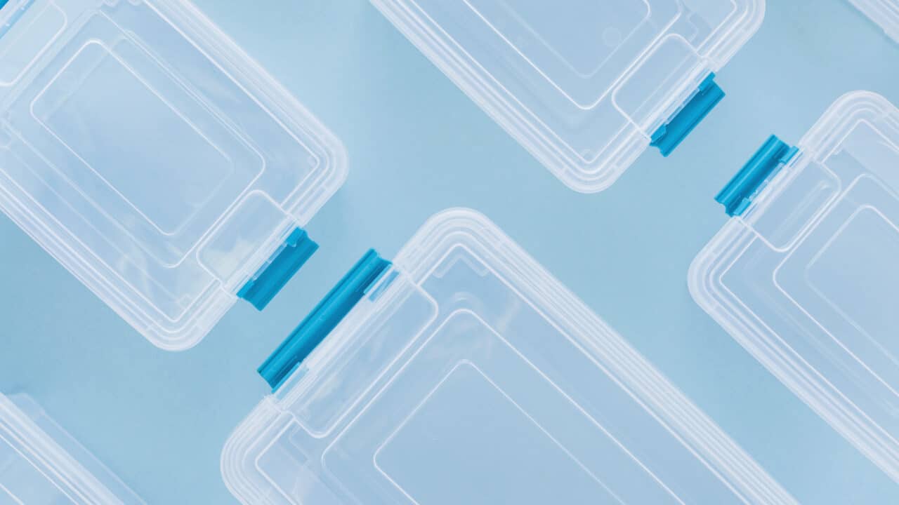 Empty divided plastic meal prep containers arranged flat lay on a neutral surface