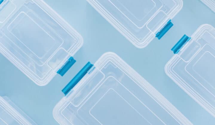 Empty divided plastic meal prep containers arranged flat lay on a neutral surface