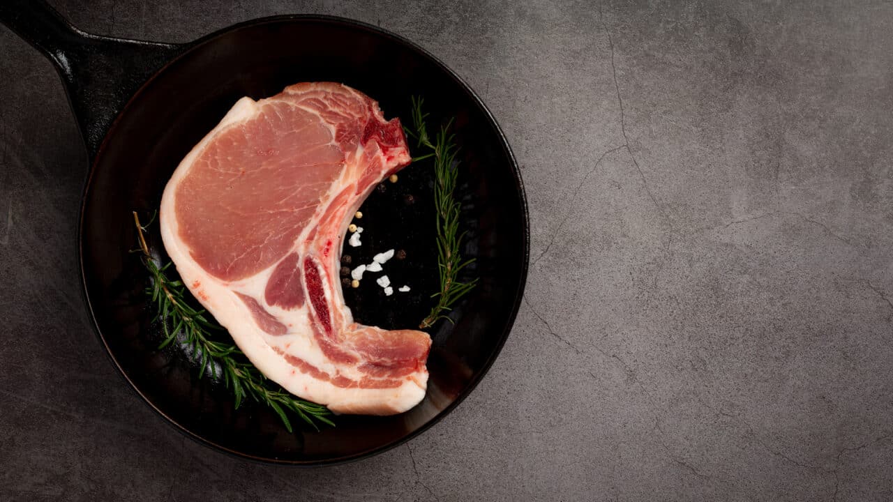 Raw pork chop on a dark neutral surface