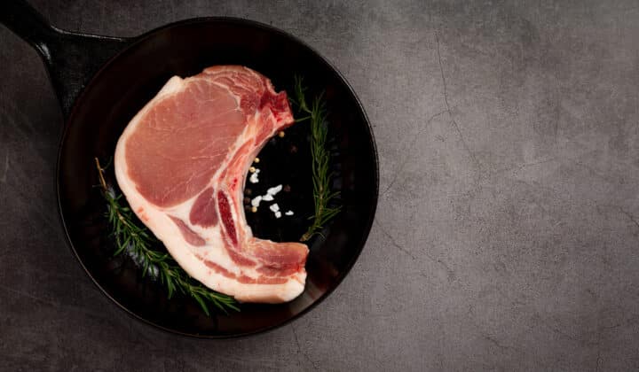 Raw pork chop on a dark neutral surface