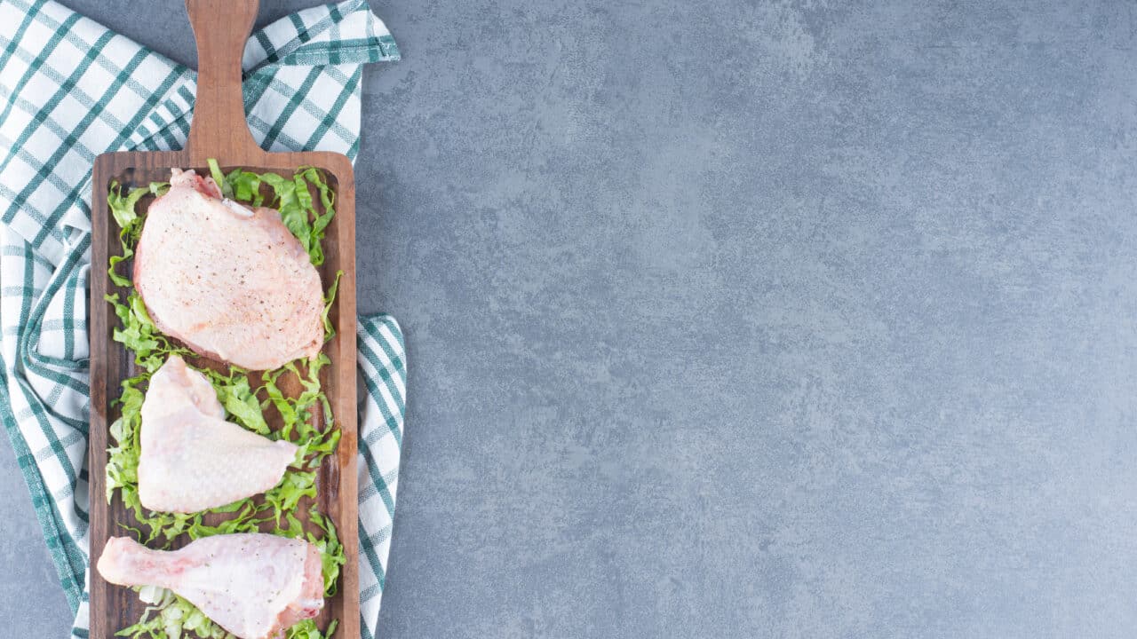 Raw chicken pieces on a wooden board