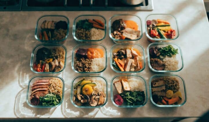 Batch cooking session with meal-prep containers arranged in a grid, overhead view