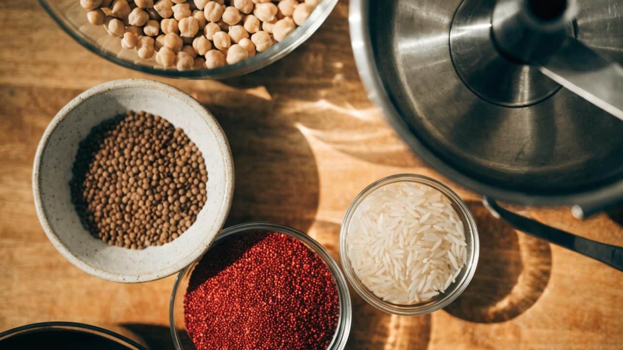 Raw dried legumes and grains for batch cooking with a Thermomix, in bowls on a wooden countertop