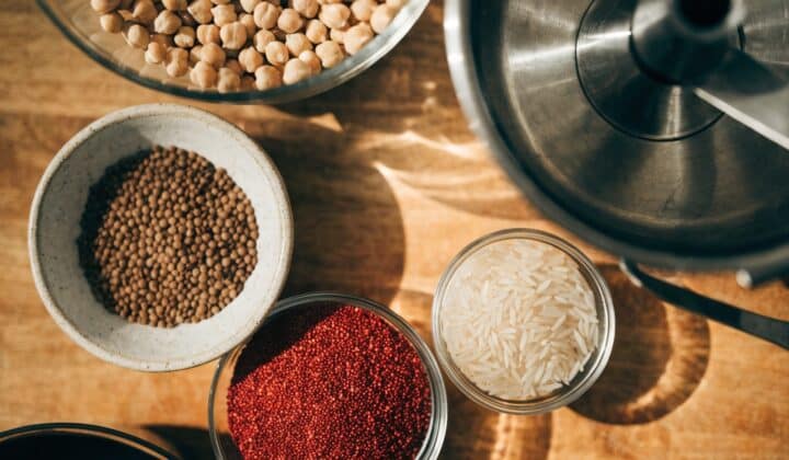 Raw dried legumes and grains for batch cooking with a Thermomix, in bowls on a wooden countertop