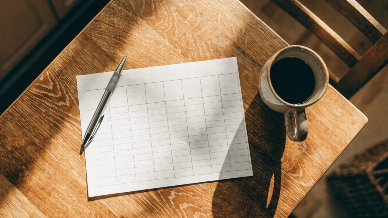 Blank weekly meal planner grid on a kitchen table, top-down view