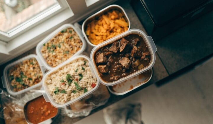 Meal prep containers filled with food, ready to freeze, top-down view