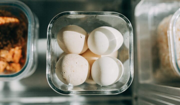 Peeled and unpeeled hard-boiled eggs stored in a container in the fridge
