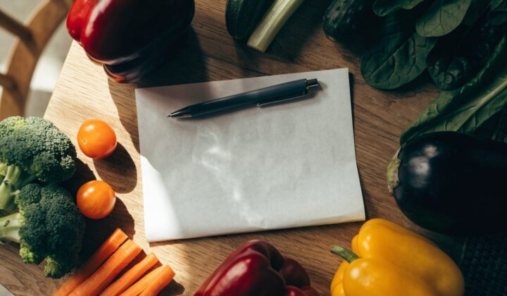Weekly meal plan sheet with fresh vegetables seen from above