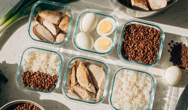 Weekly protein meal prep with chicken, eggs, lentils and rice in containers, top-down view