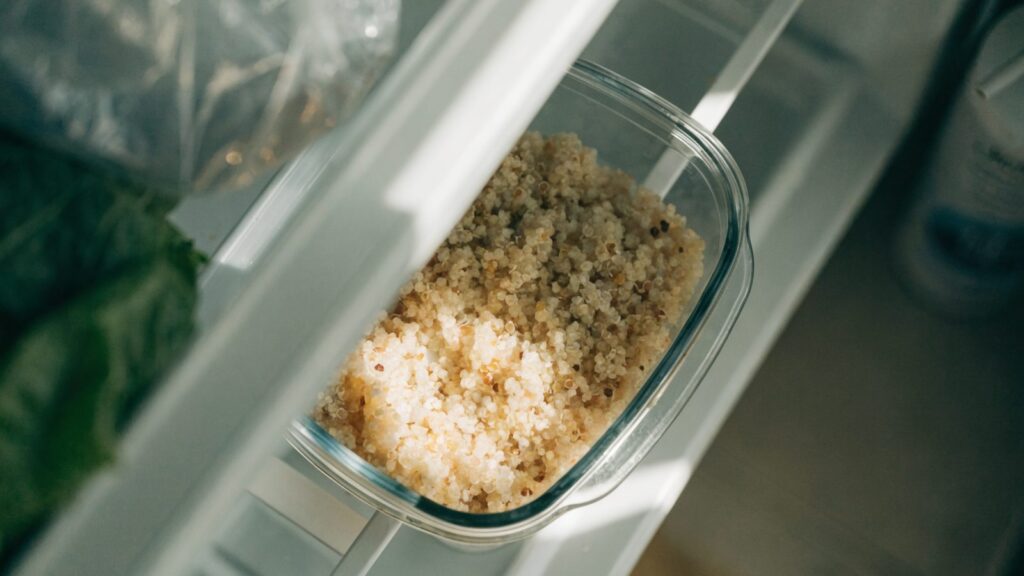 Cooked quinoa in a glass container inside the fridge