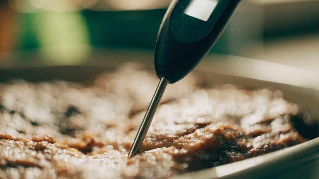 A digital food thermometer inserted into a cooked dish showing a temperature reading