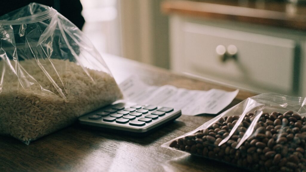A bag of dried rice and beans next to a calculator and a grocery receipt