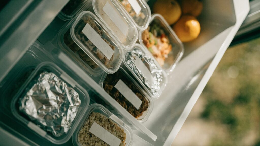 A refrigerator shelf organized with labeled, dated meal prep containers
