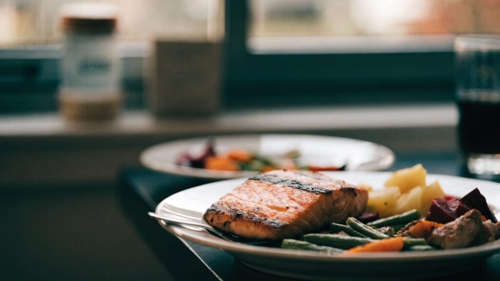 A grilled salmon fillet plated with roasted vegetables