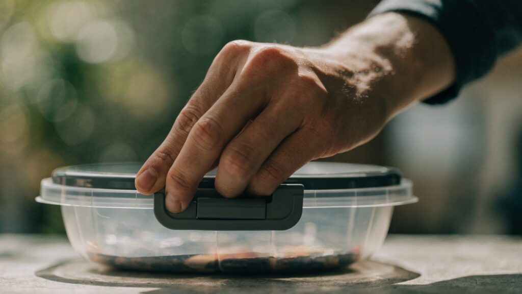 A hand snapping the clip latches shut on an airtight container lid