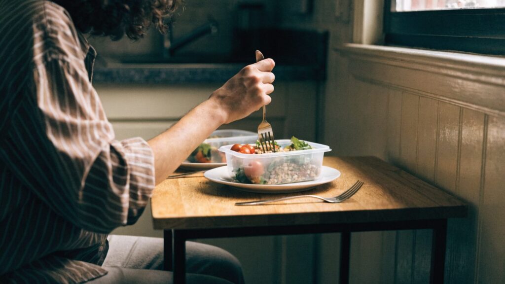 One person eating a meal prep lunch at a small kitchen table