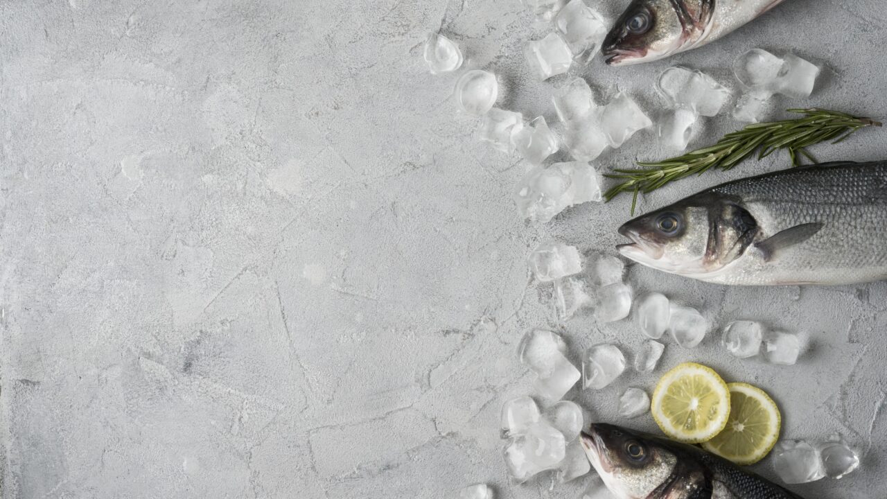 Pescado fresco entero sobre hielo con rodajas de limón y romero