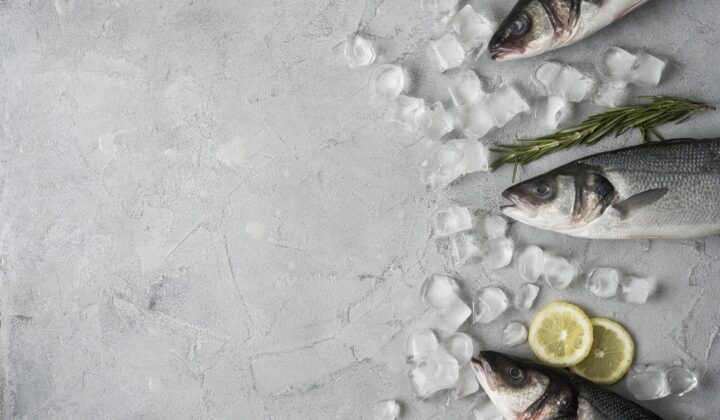 Pescado fresco entero sobre hielo con rodajas de limón y romero